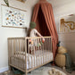 Photo of a child in a cot with a rust coloured canopy hanging over one end with some toys on the floor, looking at an art print. Our animals of the world art print consists of pictures of animals from around the world representing each letter of the alphabet, including a panda, kangaroo, viper and chameleon. Has text at the top saying animals of the world in large font and the text - An alphabet of just 26 of the wondrously, amazing 8.7 million animal species living on earth in brackets as a sub heading.