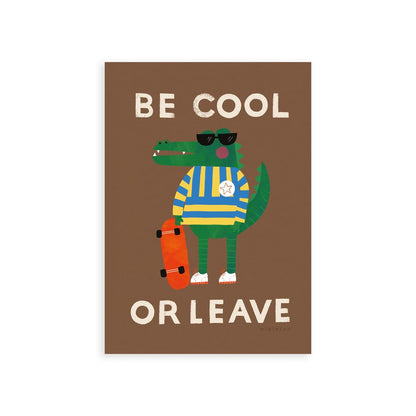 Our be cool or leave art print show a crocodile in a yellow and blue striped jumper and sunglasses, standing on his hind legs holding a skateboard, with the words be cool or leave in an off-white on a brown background.